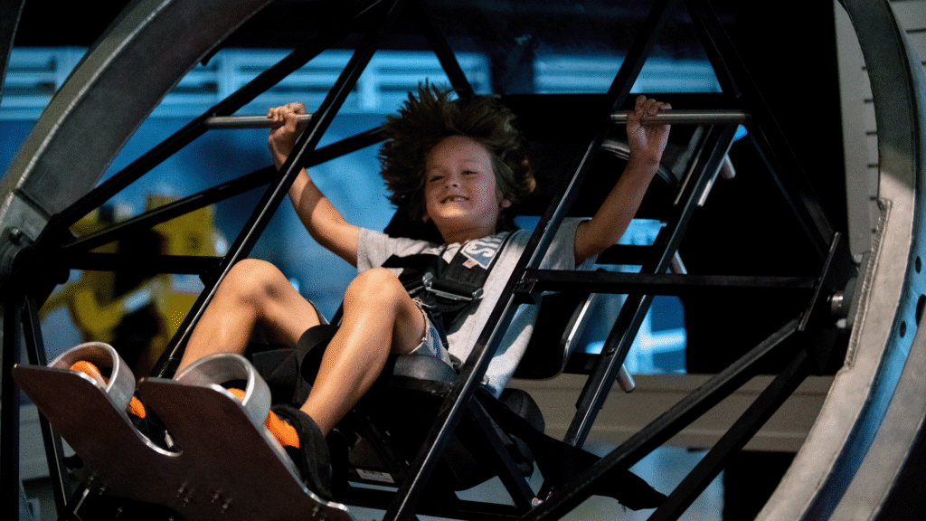 Child strapped into the multi-axis trainer, smiling