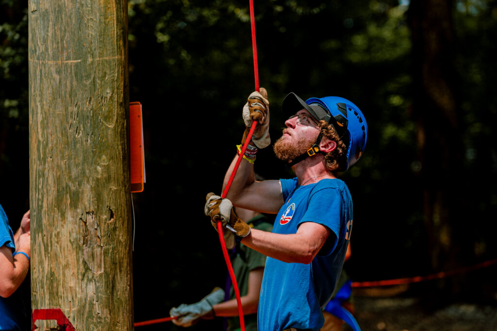 One of our ropes course employees working hard to get a camper up the pamper pole safely