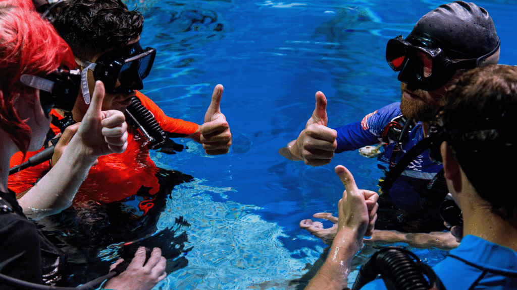 Trainees in scuba gear giving thumbs up in the Underwater Astronaut Trainer