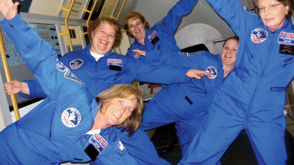 Educators in blue flight suits floating in a reduced-gravity simulator