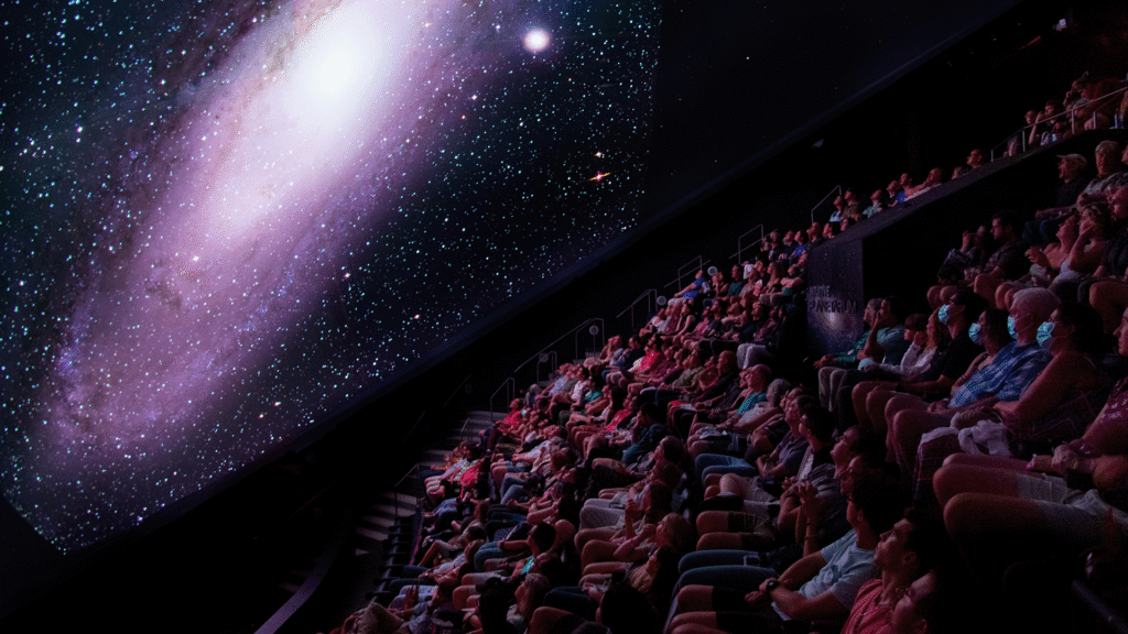 Audience in the planetarium dome watching a galaxy projection