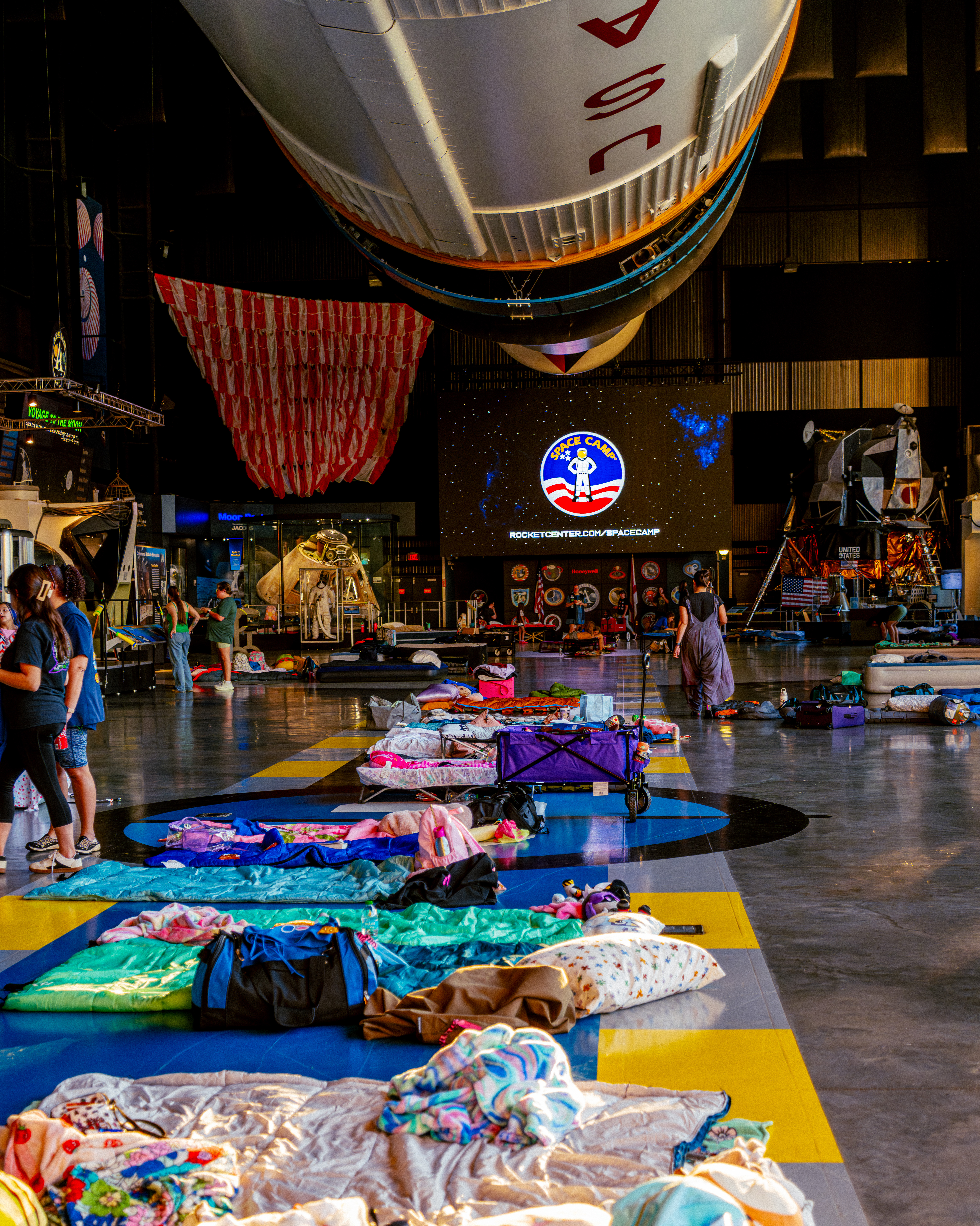Overnight Snoozeum campers' sleeping bags laid out under the Saturn V