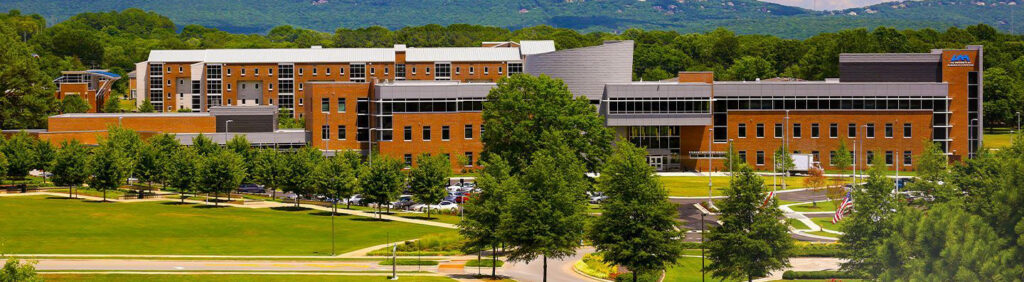 University campus building surrounded by trees with mountains behind